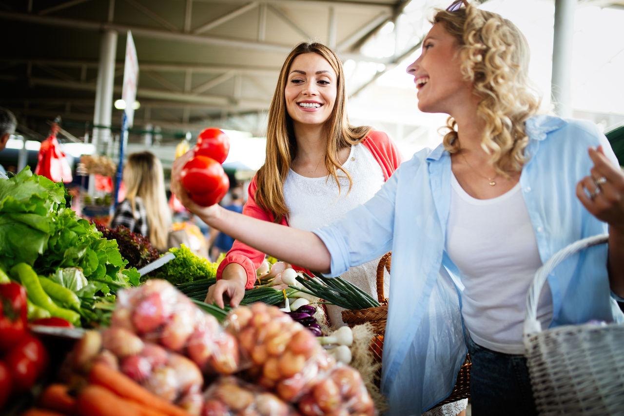 Young happy women shopping vegetables and fruits on the market